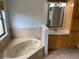 Inviting bathroom with a soaking tub, tile accents, and a vanity featuring a sink and cabinet storage at 1011 Chance Cv, Oviedo, FL 32765