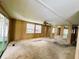 Spacious living room with wood paneling, ceiling fan, carpet flooring, and sliding glass doors to a sunroom at 106 Azalea Trl, Leesburg, FL 34748