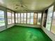 Cozy sunroom encased in windows with a ceiling fan and green carpet at 106 Azalea Trl, Leesburg, FL 34748