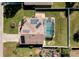 Aerial view of a home with solar panels and screened pool surrounded by a green lawn at 115 Henue Ct, Davenport, FL 33896