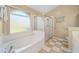 Bathroom featuring a large soaking tub, separate glass shower, and checkered tile floor at 115 Henue Ct, Davenport, FL 33896