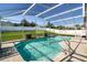 Inviting screened-in pool featuring clear water, stone patio and a well-manicured lawn at 115 Henue Ct, Davenport, FL 33896