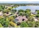 Aerial view of a home with a screened pool and lake views, surrounded by mature trees and greenery at 1502 Hempel Ave, Windermere, FL 34786