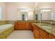 Relaxing bathroom featuring a soaking tub, dual vanities, granite counters, and tile flooring at 1502 Hempel Ave, Windermere, FL 34786