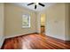 A bright bedroom with hardwood floors, a ceiling fan, and a large window overlooking lush greenery at 1502 Hempel Ave, Windermere, FL 34786