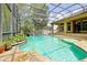 Stunning screened-in pool with stone patio, lush landscaping, and waterfall feature at 1502 Hempel Ave, Windermere, FL 34786