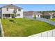 Large, landscaped backyard with white fencing, young trees, and a view of neighboring homes at 2044 Keystone Pass Blvd, Minneola, FL 34715