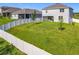 Spacious, grassy backyard featuring a white fence, young trees, and a covered patio area at 2044 Keystone Pass Blvd, Minneola, FL 34715