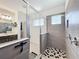 Modern bathroom featuring a glass-enclosed shower, gray tiled walls, and black and white patterned flooring at 2044 Keystone Pass Blvd, Minneola, FL 34715