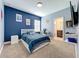 Well-lit bedroom with blue accent wall, a bed, a desk, and decor for sports fans at 2044 Keystone Pass Blvd, Minneola, FL 34715