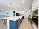 Spacious kitchen featuring modern appliances, white cabinets, a large island, and tiled flooring at 2044 Keystone Pass Blvd, Minneola, FL 34715