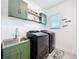 Well-organized laundry room featuring green cabinets, stainless steel sink and modern washer and dryer at 2044 Keystone Pass Blvd, Minneola, FL 34715