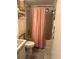 This bathroom features a pink shower curtain, a toilet, and beige tiling at 24505 Snail Rd, Astor, FL 32102