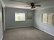 This basic bedroom with gray walls is well lit with two windows and a ceiling fan at 24505 Snail Rd, Astor, FL 32102