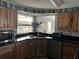 Charming kitchen boasts wood cabinets, black countertops, and natural light from a large window at 24505 Snail Rd, Astor, FL 32102
