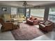 Inviting living room with ample seating, a ceiling fan, and large windows providing natural light and a comfortable atmosphere at 24505 Snail Rd, Astor, FL 32102