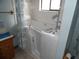 Bathroom features walk-in tub, with white tiles, and window for natural light at 360 Kentia Rd, Casselberry, FL 32707