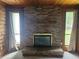Close-up of a brick fireplace with a black metal enclosure, flanked by windows with light-filtering curtains at 360 Kentia Rd, Casselberry, FL 32707