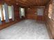 Spacious living room featuring wood-paneled walls, new grey carpet, and several windows for natural light at 360 Kentia Rd, Casselberry, FL 32707