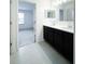 Bathroom showcasing double sinks, dark cabinetry, and an adjacent room with carpeted floors at 3850 Hampstead Ln, Lakeland, FL 33810