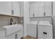 Bright laundry room includes a farmhouse sink, neutral countertops, and ample storage cabinets at 3869 Shoreside Dr, Kissimmee, FL 34746