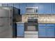 Kitchen view featuring stainless steel appliances, granite countertops, and stylish blue cabinets at 7863 Sugar Bend Dr # 7863, Orlando, FL 32819