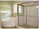 Bright bathroom featuring a glass shower and luxurious soaking tub near window at 8044 Rural Retreat Ct, Orlando, FL 32819