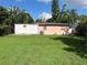 Large backyard with a pink home, a storage shed, and lush green lawn at 907 N Hyer Ave, Orlando, FL 32803