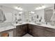 Elegant bathroom featuring dual sinks with modern fixtures, marble countertops, and decorative mirrors at 924 Figwood Loop, The Villages, FL 32163