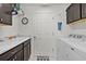 Well-lit laundry room featuring a utility sink, white appliances, and stylish dark cabinetry for ample storage at 924 Figwood Loop, The Villages, FL 32163