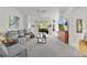 Bright living room features gray reclining seating, neutral carpeting, and sliding doors to the rear of the home at 924 Figwood Loop, The Villages, FL 32163