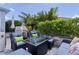Landscaped patio with comfortable seating around a glass-topped fire pit, surrounded by mature greenery and tropical plants at 924 Figwood Loop, The Villages, FL 32163