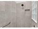 Modern shower with gray tiled walls, a built-in niche, a rainfall shower head, and a glass block window at 924 Figwood Loop, The Villages, FL 32163
