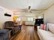 Comfortable living room with ceiling fan, wood floors, and open view to dining area at 103 Poinsettia Cv, Leesburg, FL 34748