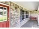 Inviting front porch with brick accent wall, hanging bench, window and red door at 1330 Englewood Dr, St Cloud, FL 34772