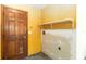 A yellow laundry room features a wooden door, white shelving, and washer and dryer hookups at 1330 Englewood Dr, St Cloud, FL 34772