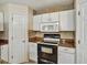 Close up of the Kitchen's stove and microwave against the tiled backsplash and white cabinets at 310 Dagama Ct, Kissimmee, FL 34758
