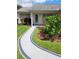 Close up on front yard with walkway leading to the front door and lush, well-maintained landscaping at 527 San Pedro Dr, The Villages, FL 32159