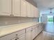 Long stretch of white cabinets and countertops with backyard view at 235 Anastasia Dr, Poinciana, FL 34759