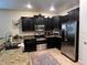 Modern kitchen with dark cabinets, granite counters, and stainless steel appliances at 1440 Moon Valley Dr, Davenport, FL 33896