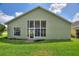 Expansive backyard with lush lawn, showcasing the home's large windows and door to the interior at 705 Ashton Dr, Davenport, FL 33837