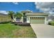 Inviting single-story home featuring a well-manicured lawn, a two-car garage, and vibrant landscaping at 705 Ashton Dr, Davenport, FL 33837
