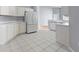 Open kitchen with white cabinets, stainless steel refrigerator, and tiled floor at 705 Ashton Dr, Davenport, FL 33837