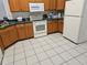 Functional kitchen featuring wood cabinets, white appliances, tile floors, and ample counter space at 959 Nancy Ct, Kissimmee, FL 34759