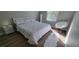 Bright bedroom featuring a plush white comforter, decorative headboard, wood floors, and a papasan chair by the window at 2307 Butterfly Palm Way # 201, Kissimmee, FL 34747