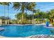 Large community pool with comfortable lounge seating, surrounded by palm trees and manicured landscaping at 441 Mayfair Dr, Kissimmee, FL 34759
