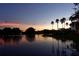 Scenic sunset view of a lake with palm trees, a fountain, and a colorful sky reflecting on the water at 441 Mayfair Dr, Kissimmee, FL 34759