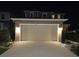 Exterior front view of the house at night with a well-lit two-car garage, driveway, and landscaped yard at 1134 Forest Gate Cir, Haines City, FL 33844