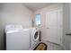 Functional laundry room with washer, dryer, neutral tile flooring, and a bright window at 1134 Forest Gate Cir, Haines City, FL 33844