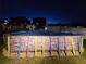 Backyard view of covered above-ground pool at night, with colorful support beams and chairs surrounding the fenced-in area at 1134 Forest Gate Cir, Haines City, FL 33844